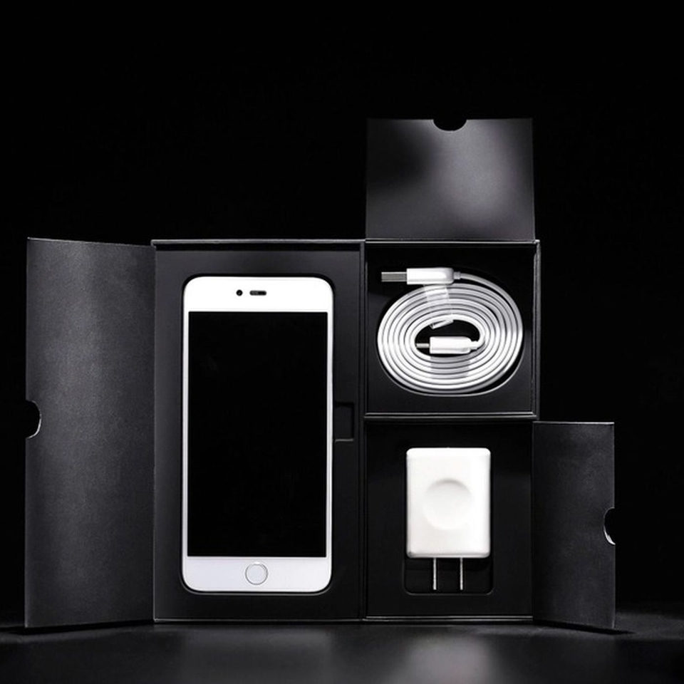 A phone and its charger, unboxed on black